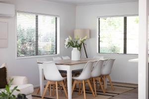 a dining room with a wooden table and white chairs at Kopanga House - Havelock North Village in Havelock North