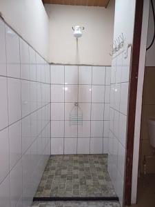 a bathroom with white tiled walls and a toilet at Sol De Fati in Quepos