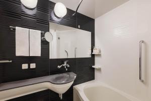 a bathroom with a sink and a mirror and a tub at Four Points Flex by Sheraton Kyoto Oike in Kyoto