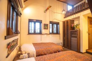 a bedroom with two beds and two windows at Estivant Club in Tsumagoi