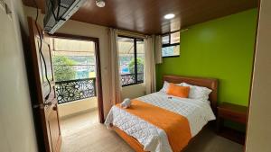 a green bedroom with a bed and a window at Vista a las 3 Maravillas de Baños in Baños
