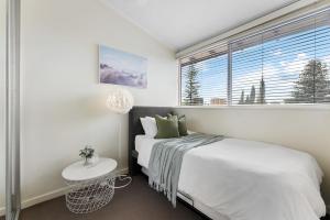 a white bedroom with a bed and a window at Pad Off Pier - 2BR, Wifi in Glenelg