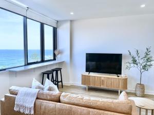 a living room with a couch and a flat screen tv at Coastal Luxe - Eats, Walks, Swims - 1 Car in Newcastle
