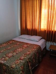 a bedroom with a bed with a blanket and a window at Mama Chelita Hospedaje in Nazca