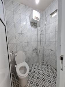a bathroom with a toilet and a tiled floor at Hazuma Homestay in Tawangmangu