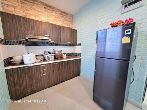 een keuken met een zwarte koelkast en houten kasten bij Plus2 Hua-Hin Private Poolvilla from beach 3km in Hua Hin
