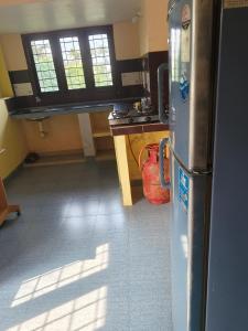 a kitchen with a refrigerator and a table with windows at Queen Mary's Homestay India kerala kochi in Cochin