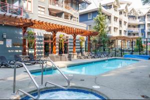a swimming pool with chairs and a building at Ideal Central Village Location! in Whistler