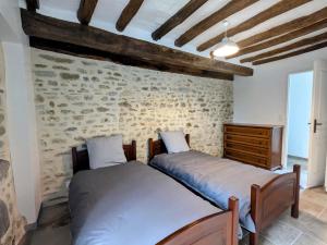 - 2 lits dans une chambre avec un mur en pierre dans l'établissement Maison familiale rénovée dans village médiéval - FR-1-591-712, à Levroux