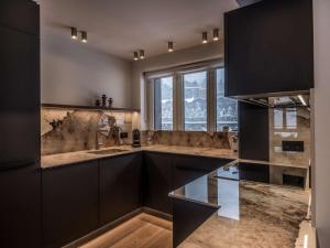 谷雪维尔Appartement ski aux pieds à Courchevel avec cheminée, parking, Wi-Fi pour 9 personnes - FR-1-631-222的一间厨房,配有黑色橱柜和大窗户 更多6张照片