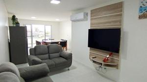 a living room with a chair and a flat screen tv at Conforto perto do Mar, Aeroporto, Beto Carrero e Balneário in Navegantes