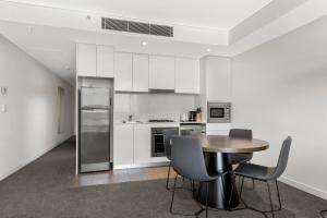 a kitchen with white cabinets and a table and chairs at One Bedroom Private Apartment at 88 Archer St Chatswood in Sydney