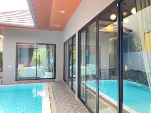 a house with a swimming pool and glass walls at Bluda Poolvilla A in Hat Yai