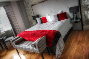 a bedroom with a bed with a red blanket and a chair at Benedicts Hotel in Belfast