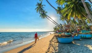 a man walking on a beach with palm trees and the ocean at BaPhu Apartment - 5BR - 5 mins walk to My Khe beach in Da Nang