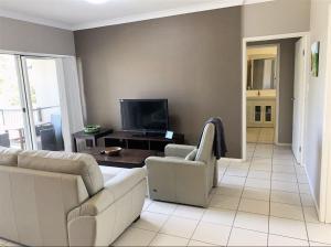 a living room with a couch and a tv at Modern Beach Apartment in Gladstone