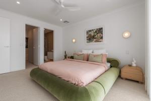 a bedroom with a large bed with a green ottoman at Sunsets Aldinga Beach, 4 king rooms, rooftop, incredible views in Aldinga Beach