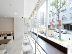 a waiting room with white chairs and a large window at Meitetsu Inn Nagoya Nishiki in Nagoya