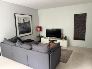 a living room with a couch and a flat screen tv at A modern two bedroom apartment! Quiet, secure and 1 minute walk to Bondi Beach! in Sydney