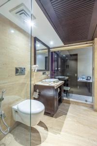 a bathroom with a toilet and a sink and a tub at Alaya Stays Hotel Emperor Palms in New Delhi