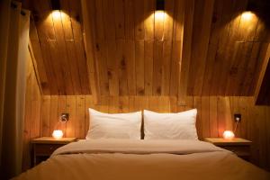 Luxury Timber Resorts and Hotels Cottages in Upper Neelum, Keran, AJK في Chak: غرفة نوم بجدار خشبي مع سرير واضاءين
