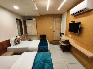 a hotel room with two beds and a television at Hotel Kinara in Ahmedabad