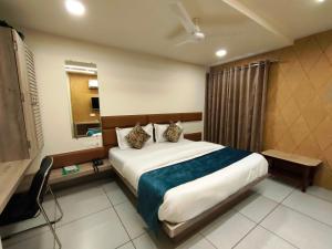 a bedroom with a large bed and a window at Hotel Kinara in Ahmedabad