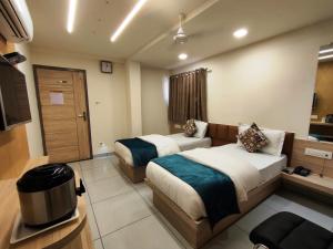 a hotel room with two beds and a television at Hotel Kinara in Ahmedabad