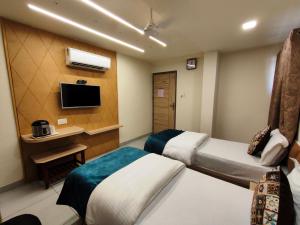 a hotel room with two beds and a television at Hotel Kinara in Ahmedabad