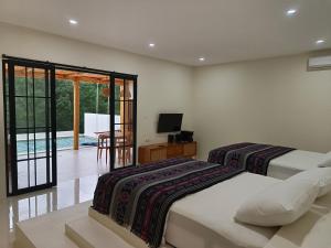 two beds in a room with a television and a table at Villa Fortuna - PANDAWA #Puncak Bogor in Megamendung