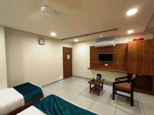 a hotel room with a bed and a desk and a television at Hotel Kinara in Ahmedabad