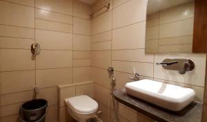 a bathroom with a sink and a toilet and a mirror at Hotel Kinara in Ahmedabad