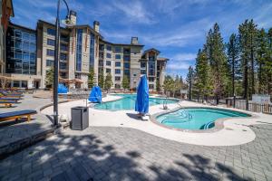 a swimming pool with blue umbrellas in front of a building at Updated Pet Friendly Monache Studio with Views! in Mammoth Lakes