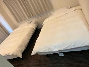 two beds in a bedroom with white sheets at 山中ビル3Fーワンフロア貸切48平方メートルone floor private room in Warabi