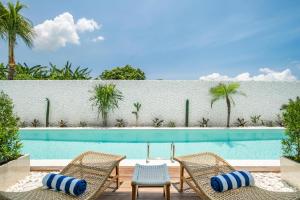 a swimming pool with two chairs next to a fence at Baliterraneo Boutique Resort in Seminyak
