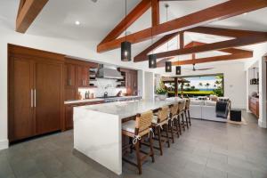 una cocina con armarios de madera y un bar con sillas en Kukuiula Vacation Home #57, en Koloa