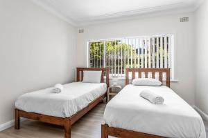 two beds in a room with a window at Kaleula Upper Beach House in Kiama
