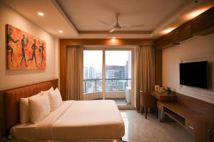 a hotel room with a bed and a desk and a television at Alivaa Hotel Gurugram Sohna Road City Center in Gurgaon