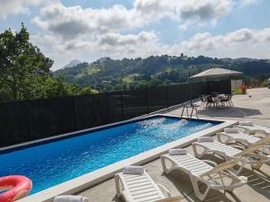 a swimming pool with chairs and a group of tables and chairs at La Casona de Llovio próxima a Ribadesella in Llovio