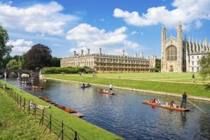 people in boats on a river in front of a building at Great Central self-contained flat in Cambridge