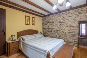 ein Schlafzimmer mit einem Bett und einer Steinwand in der Unterkunft O forno do curro-Casiña Da Avelá in Boborás