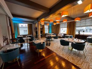 a restaurant with tables and chairs in a room at The Originals Boutique, Hôtel Auberge du Forgeron, Lille Sud in Seclin