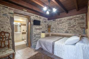 ein Schlafzimmer mit einem Bett und einer Steinwand in der Unterkunft O Forno do Curro -Casa da Amendoa in Boborás + 27 Fotos