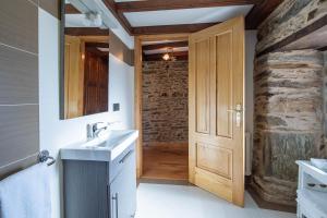 a bathroom with a sink and a wooden door at O forno do curro- Casiña da Noz in Boborás +17 photos