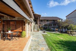eine Terrasse eines Hauses mit einem Tisch und Stühlen in der Unterkunft O Forno do Curro -Casa da Amendoa in Boborás