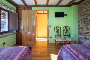 ein Zimmer mit zwei Betten und einer Tür und zwei Stühlen in der Unterkunft O Forno do Curro -Casa da Amendoa in Boborás