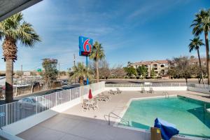 a swimming pool with palm trees and a hotel at Motel 6-Phoenix, AZ - East in Phoenix