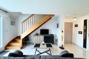 a living room with a staircase and a couch at Joli duplex plein bourg - 4km des plages in Guidel