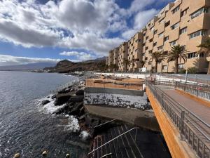 a building next to a body of water with palm trees at Alquilaencanarias Tabaiba vista mar in Tabaiba
