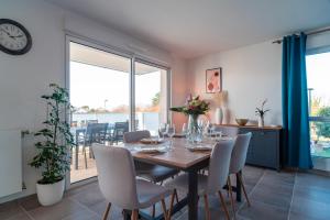 ein Esszimmer mit Tisch und Stühlen und einer Uhr in der Unterkunft Le Jardin du Golfe - En centre-ville avec parking in Sarzeau